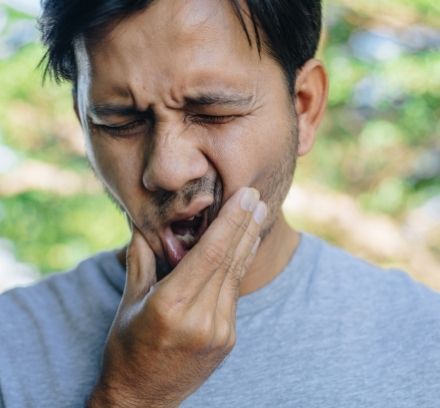 Man holding his mouth, perhaps with wisdom teeth sensitivity to heat